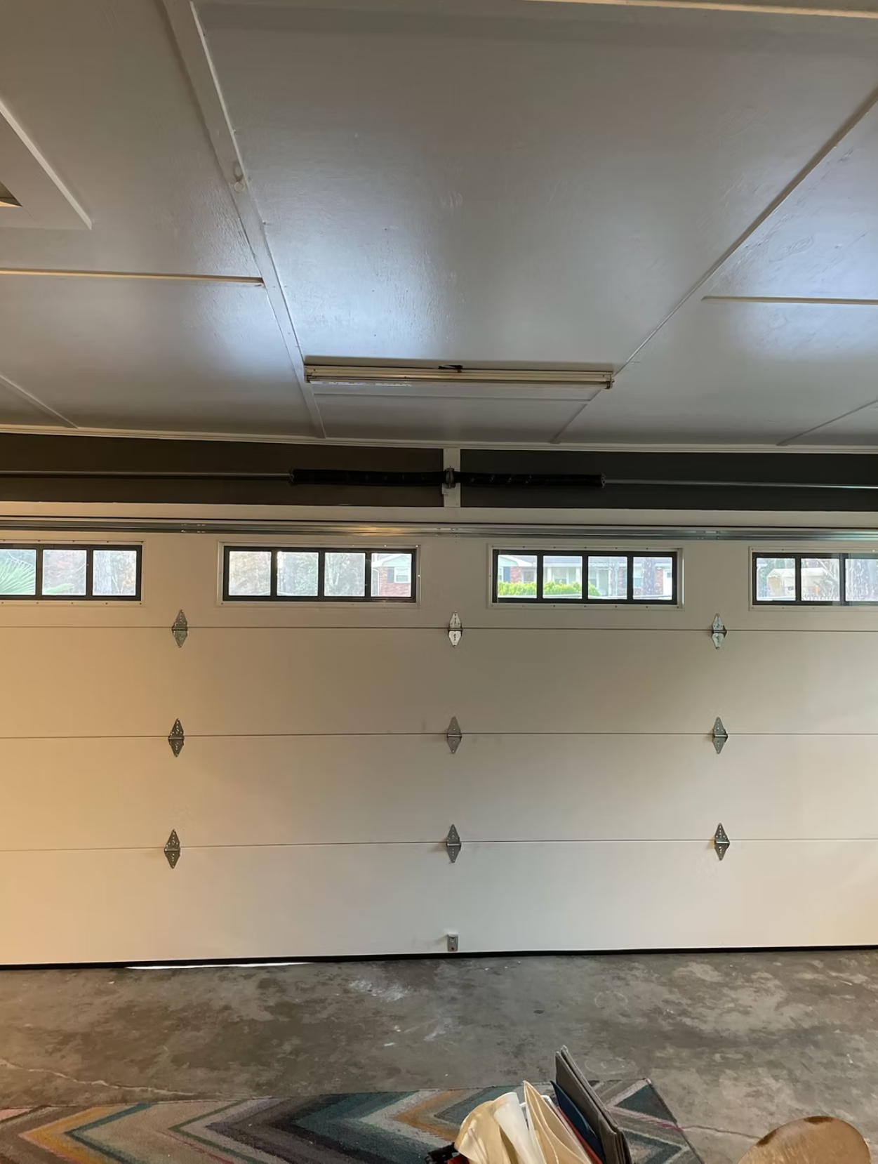 Interior of empty residential garage with white door and small windows near ceiling